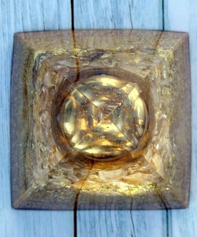 Pirámide grande de orgonita con bola metálica dorada sobre piezas de CITRINO